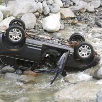 A car sits upside down in the Nakagawa River in Yamakita, Kanagawa Prefecture, on Saturday morning after a family of four was washed away while attempting to drive across it amid heavy rain the previous day. Only the father survived. | KYODO