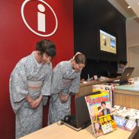 Alia Carter (left) from the United States and Paloma Free from Spain welcome foreign tourists at Coredo Muromachi’s information counter in Tokyo’s Nihonbashi district on July 19. | YOSHIAKI MIURA