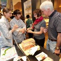 Carter and Free explain dried bonito products to two American tourists. | YOSHIAKI MIURA