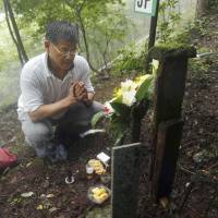 Masayuki Teranishi, 52, who lost his younger brother, Masatsugu, when Japan Airlines Flight 123 went down on Aug. 12, 1985, prays on a hillside at the crash site in Gunma Prefecture on Tuesday, the 29th anniversary of the world’s worst single-plane disaster, which claimed 520 lives.  | KYODO