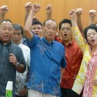 Okinawa Gov. Hirokazu Nakaima (center) thrusts his fist into the air alongside supporters in July after the local chapter of the Liberal Democratic Party asked to run for re-election. | KYODO