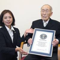 Sakari Momoi, 111, recognized as the world\'s oldest man by Guinness World Records, receives a certificate from a company representative on Wednesday in Tokyo. | KYODO