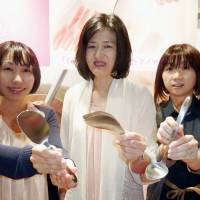 Noriko Ishiwata (center) and her colleagues at household goods maker Aux Co. show off some of the inventive new kitchen utensils they developed. | KYODO