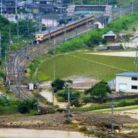 A train is stopped Sunday afternoon on the JR Fukuchiyama Line after a rain-triggered mudslide covered the tracks near Tambatakeda Station in Tamba, Hyogo Prefecture. | BLOOMBERG
