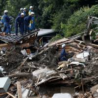 Volunteers sought: Police officers and a Self-Defense Force soldier search for landslide survivors amid the debris in Asaminami Ward, Hiroshima, on Saturday. Hiroshima volunteer cleanup effort open to city residents