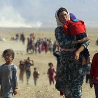 Iraqis from the minority Yazidi sect, fleeing violence from the Islamic State, walk toward the Syrian border on Monday. The militants have executed at least 500 Yazidis, prompting tens of thousands to flee for their lives. | REUTERS
