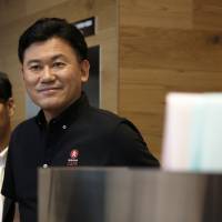 Billionaire Hiroshi Mikitani, chairman and chief executive officer of Rakuten Inc., smiles during the opening of Rakuten Cafe in Tokyo in May. | BLOOMBERG