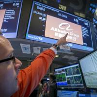A trader points to the \"BABA\" ticker symbol for Alibaba Group Holding Ltd. during its initial public offering at the New York Stock Exchange on Friday. SoftBank Corp. on Saturday predicted a gain of around &#36;4.6 billion through its stake in the Chinese e-commerce behemoth. | REUTERS