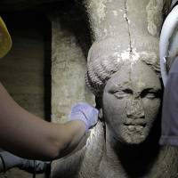 In this photo released on Sept. 7 by the Greek Culture Ministry, archaeologists inspect a 60 cm female figurine on a wall leading to the yet unexplored main room of an ancient tomb, in the town of Amphipolis, northern Greece. The tomb dates between 325 B.C. — two years before the death of ancient Greek warrior-king Alexander the Great — and 300 B.C. | AP