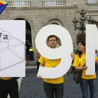 Catalonian separatists hold placards representing the Nov. 9 independence referendum in front of Generalitat Palace before Catalonia President Artur Mas signed a decree Saturday calling for the vote, in Barcelona. | REUTERS