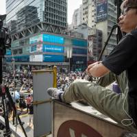 A cameraman monitors pro-democracy demonstrators in Hong Kong on Tuesday. Tens of thousands of pro-democracy protesters turned parts of the city into a massive street party on Monday night, with the mood turning festive just a day after riot police fired tear gas in ugly clashes. | AFP-JIJI