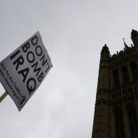 A demonstrator holds a banner near Parliament in London on Friday during a protest against Britain\'s plans to take part in airstrikes against Islamic State group militants in Iraq. | AP