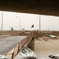 Black flags used by the Islamic State group are seen over their combat positions in the Rashad Bridge, which connects the provinces of Salah al-Din and Kirkuk, 290 km (180 miles) north of Baghdad on Monday. | AP