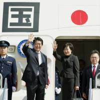 Prime Minister Shinzo Abe and his wife Akie wave before boarding a jet Monday at Haneda airport in Tokyo on the way to the U.N. General Assembly in New York. | KYODO