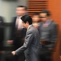 Prime Minister Shinzo Abe passes his Cabinet ministers ahead of a news conference at his office in Tokyo on March 10. | AP