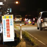 Cars enter a closed-off section of National Route 6 in the town of Tomioka, Fukushima Prefecture, near the Fukushima No. 1 nuclear plant after a ban on vehicles was lifted at midnight Sunday. | KYODO