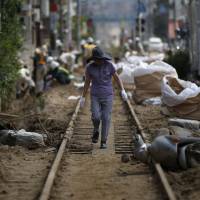 A local resident walks down tracks damaged by a landslide that swept through a residential area of Asaminami Ward in Hiroshima on Aug. 23. | REUTERS