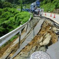 Workers in Ayabe City survey road damage that occurred due to heavy rains Thursday  in northern Kyoto. | KYODO