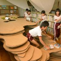 Pupils at Yoshima Daiichi Elementary School in Iwaki, Fukushima Prefecture, are encouraged to creep into the new cardboard cave in the library to enjoy reading books. | KYODO