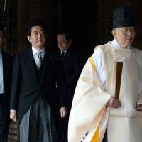 A Shinto priest leads Prime Minister Shinzo Abe during his visit to the controversial Yasukuni Shrine in Tokyo on Dec. 26 last year. | AFP-JIJI