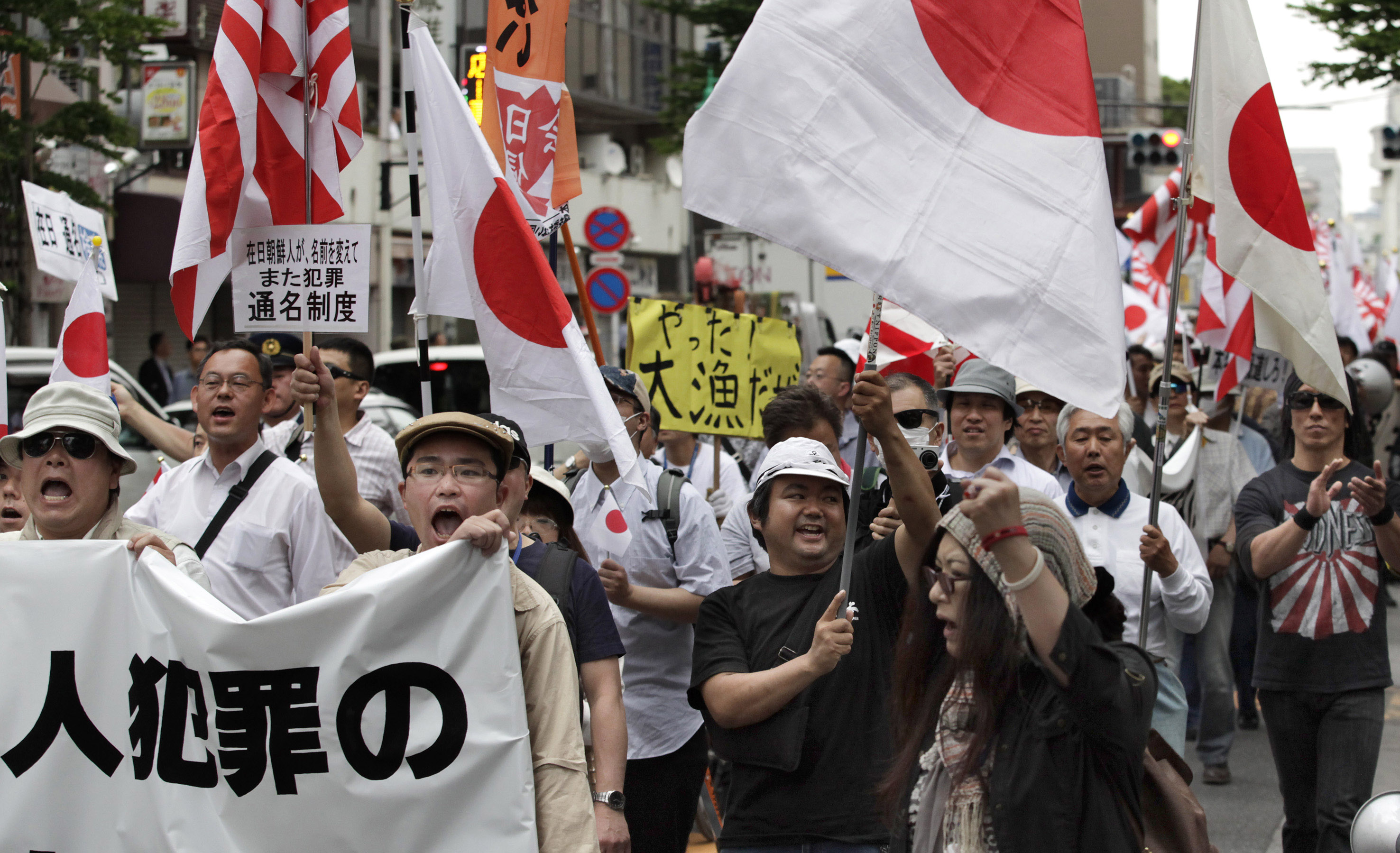 Worrisome words: In this photo taken May 19, 2013, nationalist protesters with flags march through Tokyo to denounce 'privileges' for Korean residents in Japan. Some of the demonstrators were heard shouting, 'Kill Koreans.' | AP