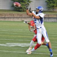 Appliance of science: Nippon Sports Science University wide receiver Genta Nakano receives a pass from Yota Tsuji as Nihon University defensive back Ken Inoue covers him during the first quarter on Saturday at Amino Vital Field. Nihon Sports Science University won 56-14. | HIROSHI IKEZAWA