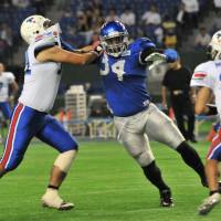 NCAA style: Former Arizona State starting defensive end James Brooks (34) of IBM pressures Tokyo Gas quarterback Ryo Murota during the first quarter on Wednesday at Tokyo Dome. The BigBlue won 69-7. | HIROSHI IKEZAWA