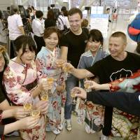 Women in kimono and foreign tourists celebrate the 20th anniversary of the opening of Kansai International Airport during an event Thursday in Izumisano, Osaka Prefecture. Since opening in 1994, the airport has seen growth in tourists from Asia and is refurbishing the No. 1 terminal building to live up to its goal of becoming a major hub. | KYODO