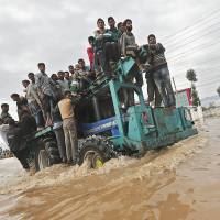 A tractor evacuating Kashmiri flood victims to higher ground churns through a street in Srinagar, northern India, on Tuesday. After weeks of army clashes in the disputed Himalayan region, India and Pakistan have offered to help each other in efforts to alleviate the flood havoc, lowering tensions. | REUTERS