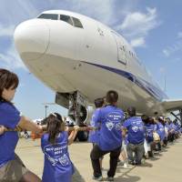 Parents and children attempt to tow a Boeing 777 on Sunday at Narita International Airport. The event was held in connection with \"Airplane Day\" on Saturday, which originates from Japan\'s first success with powered flight in 1910. | KYODO