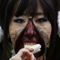 A zip-faced participant in Sunday\'s Kawasaki Halloween parade takes a sandwich parade.  | REUTERS