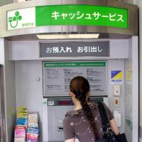 A customer uses an ATM in Tokyo. Japanese bankers mull extending hours for money transfers