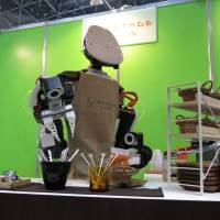 Kawada Industries Inc.\'s industrial robot Nextage serves coffee to visitors during the Japan Robot Week exhibition at Tokyo Big Sight in the Odaiba district. | KAZUAKI NAGATA