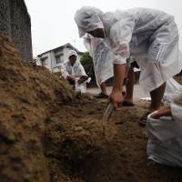Local people remove debris from a landslide that swept through a residential area in Asaminami Ward, Hiroshima, on Aug. 22 following massive rainfall. The government says this summer\'s bad weather may have pushed down economic growth. | REUTERS
