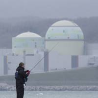 A man fishes near Hokkaido Electric Power Co.\'s Tomari nuclear plant in May 2012. | BLOOMBERG