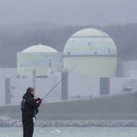 A man fishes near Hokkaido Electric Power Co.’s Tomari nuclear plant in May 2012. Hokkaido Electric to execute second price hike in November