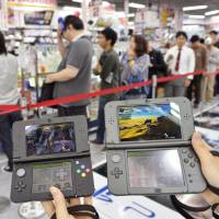 Nintendo Co.\'s new 3DS portable game consoles are shown as customers wait in line to buy them Saturday at Yodobashi Camera Co.\'s flagship store in the city of Osaka. | KYODO