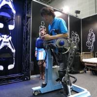 Tokyo University of Science personnel hold a demonstration with a machine that can aid people who have difficulty walking. | KAZUAKI NAGAGA