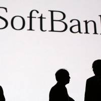 Billionaire Masayoshi Son, chairman and chief executive officer of SoftBank Corp. (center), and Colin Powell, former U.S. secretary of state (right), are silhouetted after a talk session in Tokyo in June. | BLOOMBERG