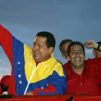 Then-Venezuelan President Hugo Chavez (left) and the candidate of their party for the parliamentary elections Robert Serra greet supporters during a rally in Caracas in 2010. Serra was found slain at his home in Caracas on Thursday. | AFP-JIJI