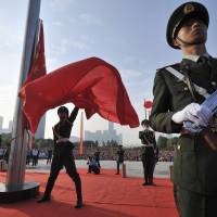 A paramilitary policeman unfurls a Chinese national flag during a ceremony to mark the 65th anniversary of the founding of the People’s Republic of China, in Hefei, Anhui province, on Wednesday. This year, the annual holiday was overshadowed in Hong Kong by sprawling pro-democracy protests, in the largest popular challenge to the ruling Communist Party in years.  | REUTERS