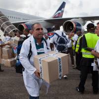 The first members of a team of 165 Cuban doctors and health workers unload boxes of medicines and medical material from a plane upon their arrival at Freetown\'s airport to help the fight against Ebola in Sierra Leone on Thursday. | AFP-JIJI