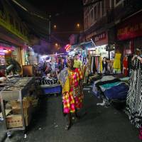 A woman walks through a market in the \"African village\" in Guangzhou, the capital of the Chinese province of Guangdong, on Oct. 25. | REUTERS