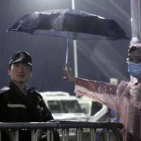 A demonstrator for democracy holds an umbrella for a police officer in Hong Kong on Tuesday. | AP