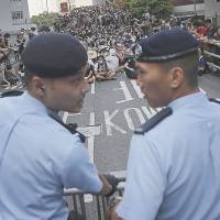 Hong Kong democracy protesters sit on the road as they face off with local police on Sept. 29. | AP