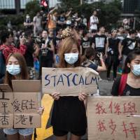 Pro-democracy demonstrators display placards as they gather near a ceremony marking China\'s 65th National Day in Hong Kong on Wednesday. | AFP-JIJI