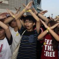 Scholarism founder and protest leader Joshua Wong (center) and other demonstrators chant slogans during a flag-raising ceremony in Hong Kong on Wednesday. | REUTERS