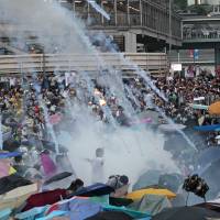 Riot police launch tear gas into the crowd as thousands of pro-democracy protesters surround the government headquarters in Hong Kong on Sept. 28. | AP