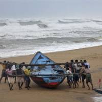 Fishermen move a fishing boat to a safer place as Cyclone Hudhud approaches the Ganjam district of Orissa state on Saturday. Two die as powerful Cyclone Hudhud lashes east Indian coastal area