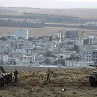 Turkish soldiers hold their positions in tanks on a hilltop on the outskirts of Suruc, at the Turkey-Syria border, overlooking Kobani, Syria, during fighting between Syrian Kurds and militants from the Islamic State group on Friday. | AP